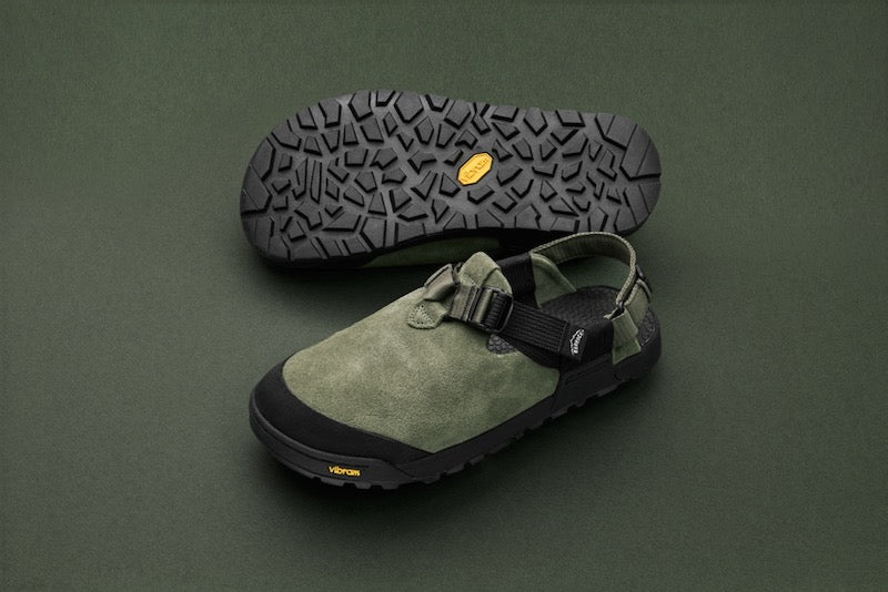 studio photo of sagebrush green leather suede mountain clogs with green backdrop