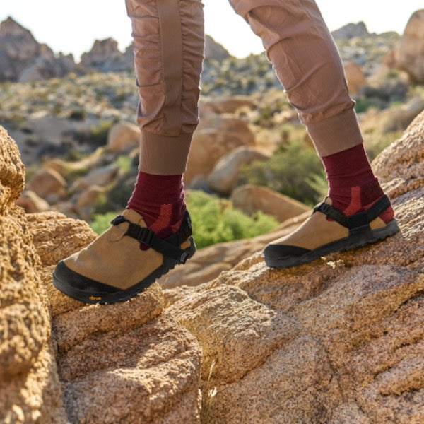Person wearing Mountain Clog and red socks on rocky terrain