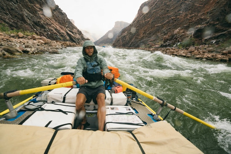 person whitewater rafting in the rain through a rapid wearing cairn evo 3d pro sandals