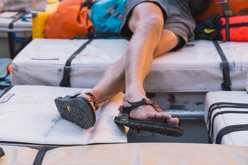 someone on a whitewater raft wearing clay strapped cairn evo pro sandals