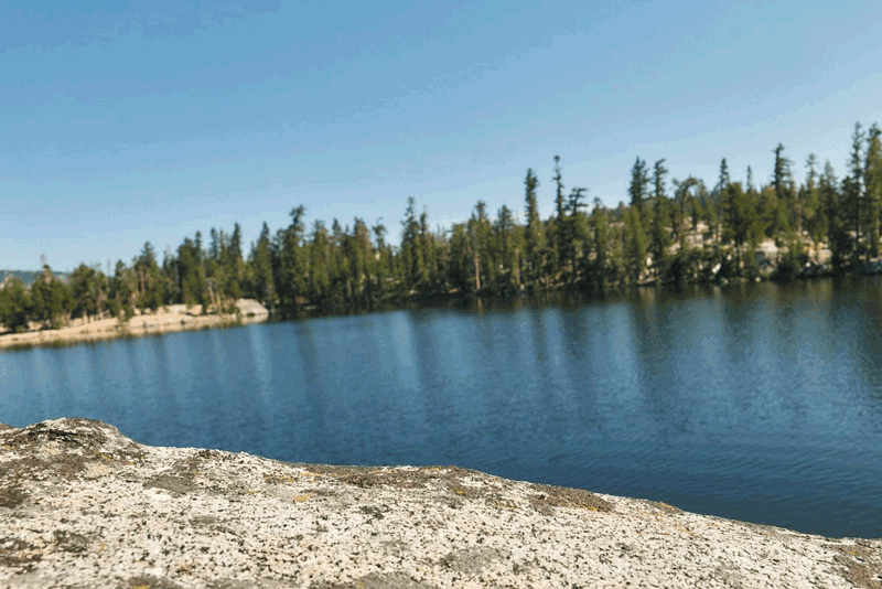 person cliff jumping off a granite rock into an alpine lake