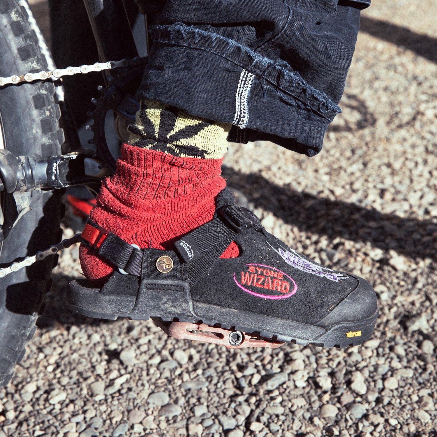 Person wearing Stone Wizard phantom black clogs while pedaling a bike