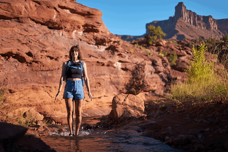 person jumping in a creek in the desert in cairn evo pro sandals