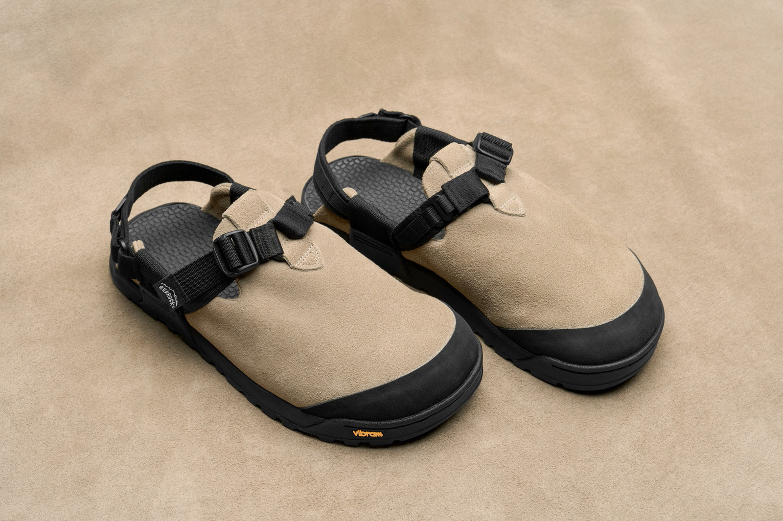 pair of birch bark tan leather suede mountain clogs with a tan studio backdrop