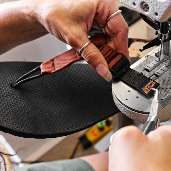 Person repairing sandal and sewing on new strap