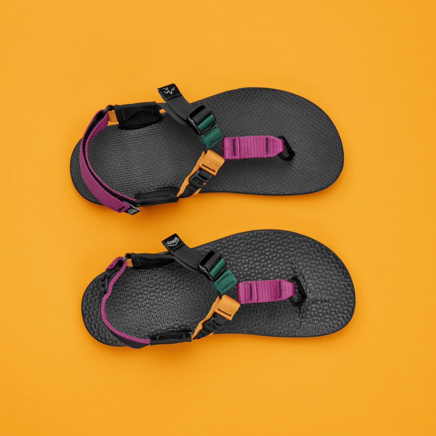 Two Metamorphic Tourmaline Cairn Sandals side by side on a yellow background showing the different footbed styles available.