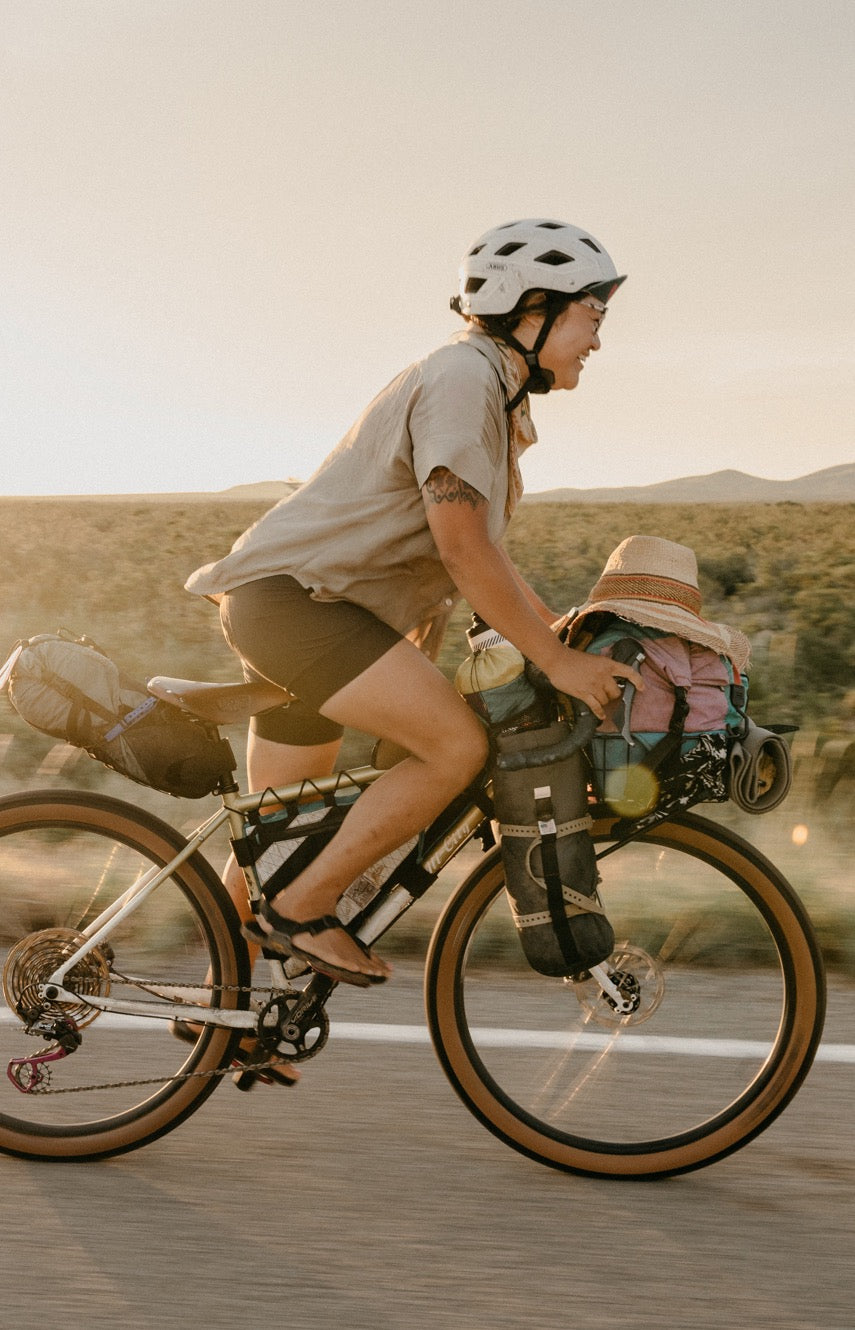 Person riding a bicycle on a road with a scenic background