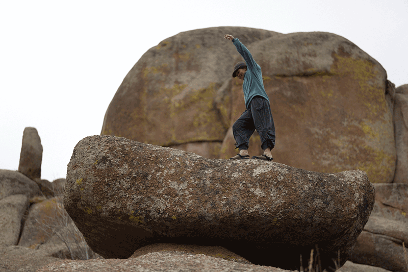 person walking along large boulder wearing gray nubuck leather mountain clogs 