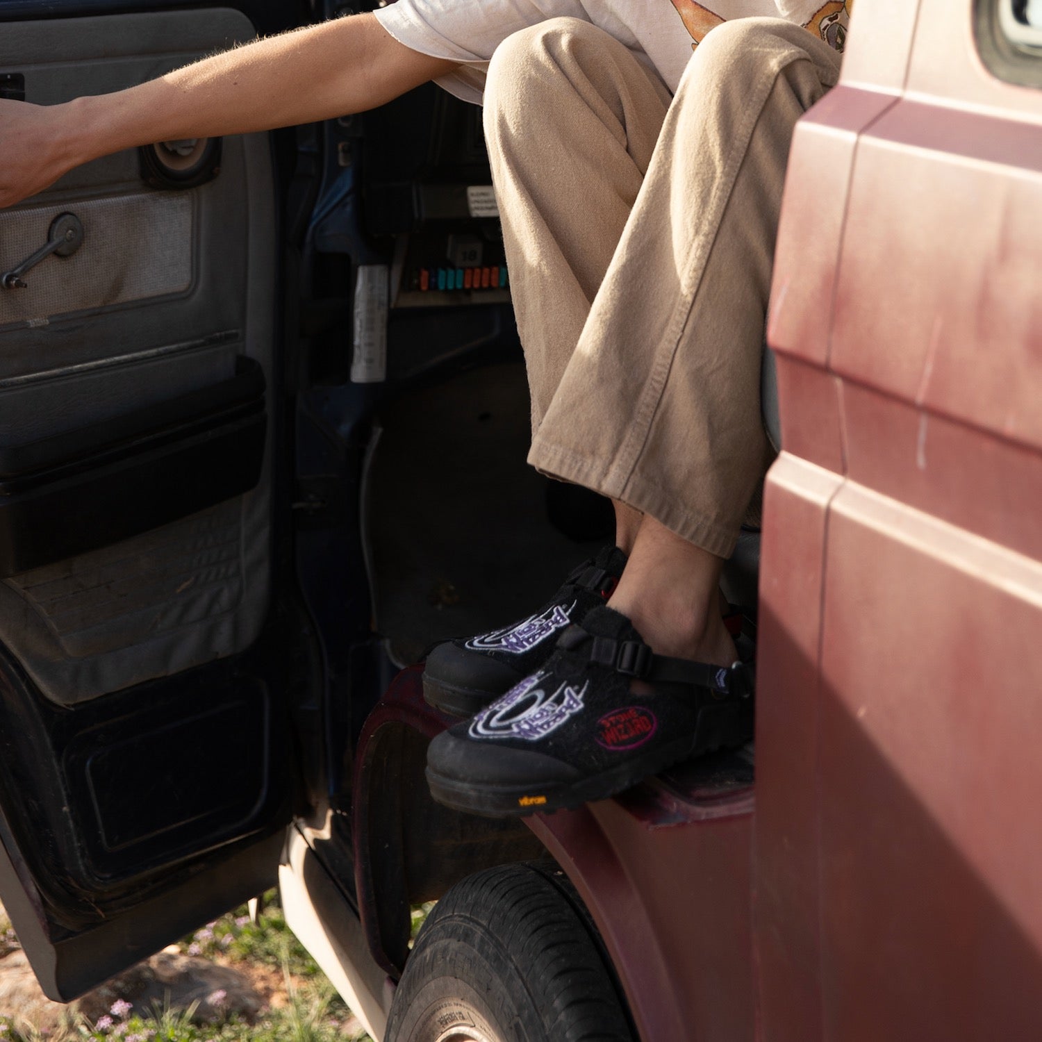 Person sitting in a vehicle with feet wearing Stone Wizard phantom black clogs