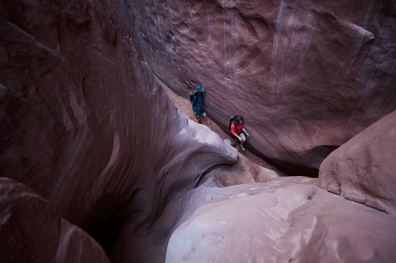two people walking through a slot canyon in bedrock cairn sandals