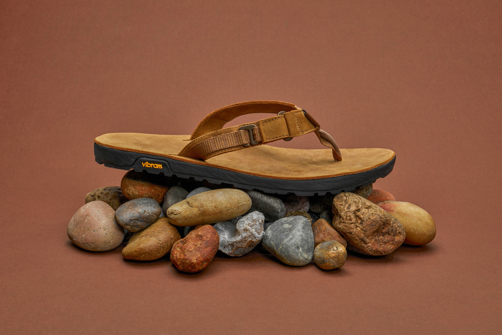Nubuck Rockhound sandal on a pile of multicolored stones against a brown background